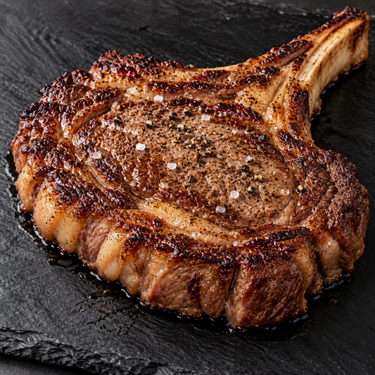 Tomahawk Steak fertig gegrillt mit Salz und Pfeffer