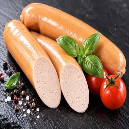Geflügel Bockwurst auf dunkler Schieferplatte mit Tomaten und Basilikum